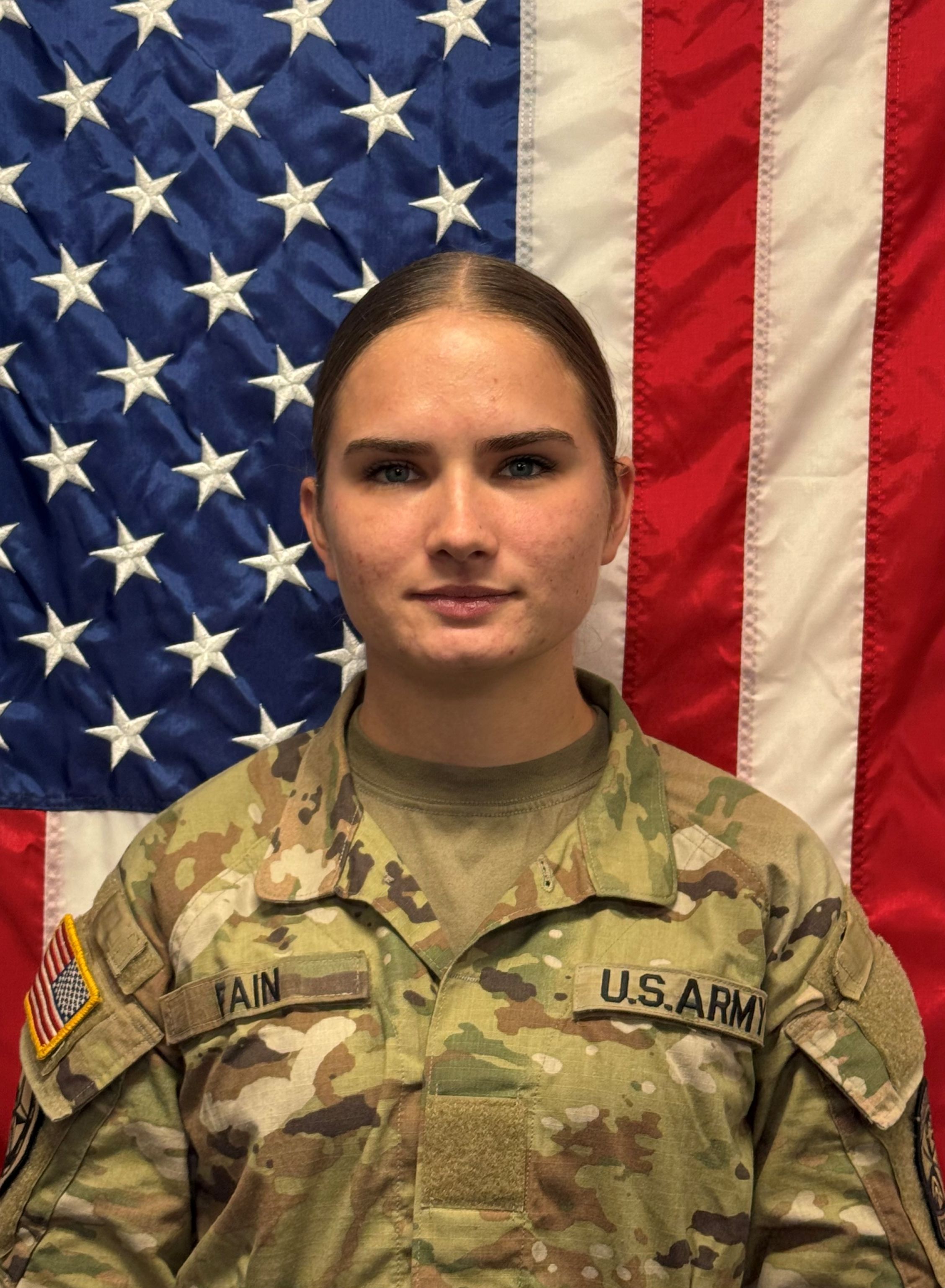 Cadet Fain standing in front of a U S A flag in uniform.