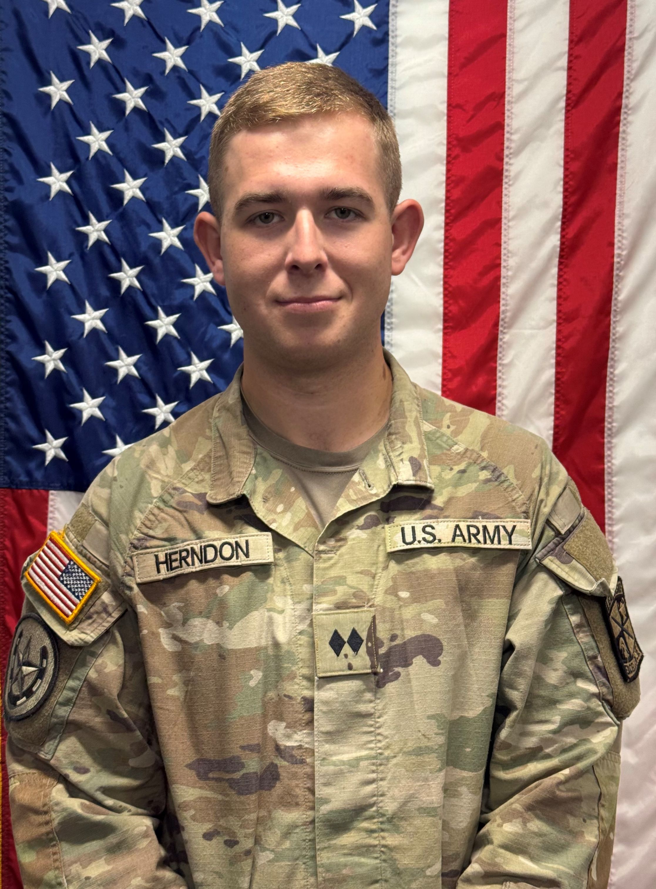 Cadet Herndon standing in front of a U S A flag in uniform.