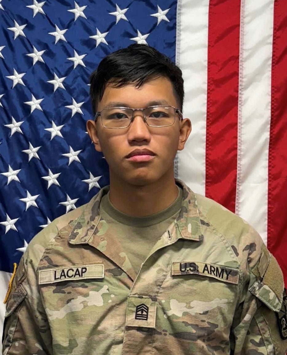 Cadet Lacap standing in front of a U S A flag in uniform.