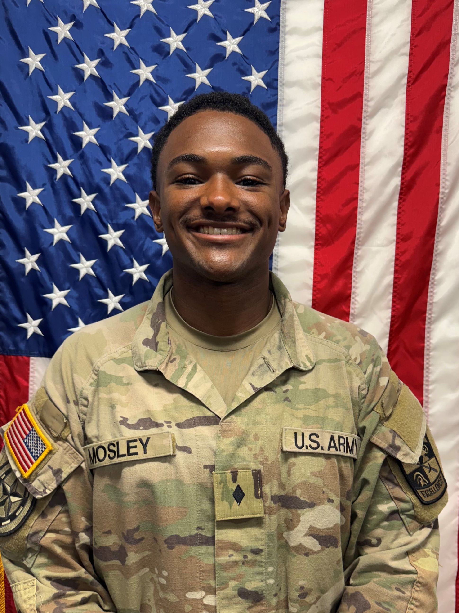 Cadet Mosley standing in front of a U S A flag in uniform.