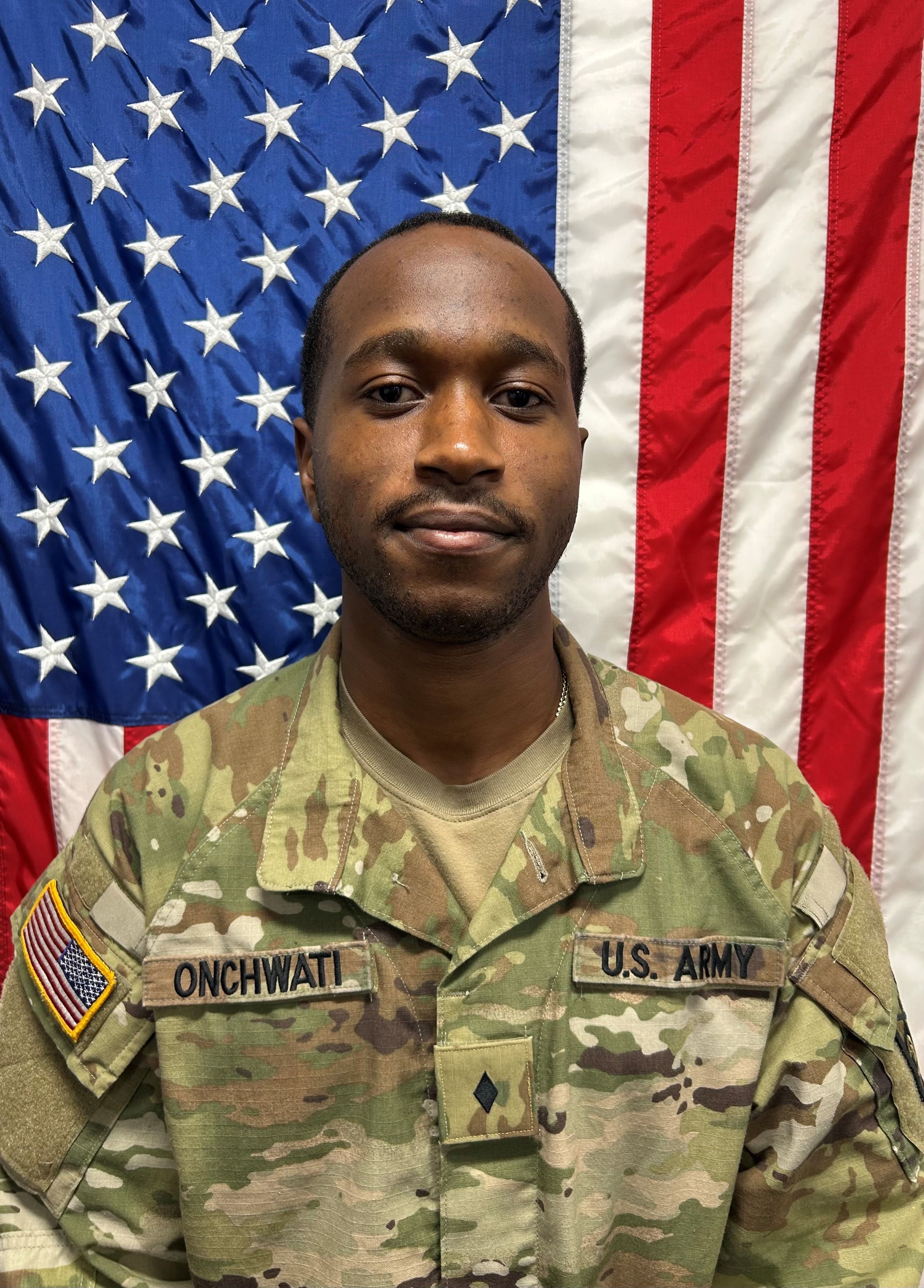 Cadet Onchwati standing in front of a U S A flag in uniform.