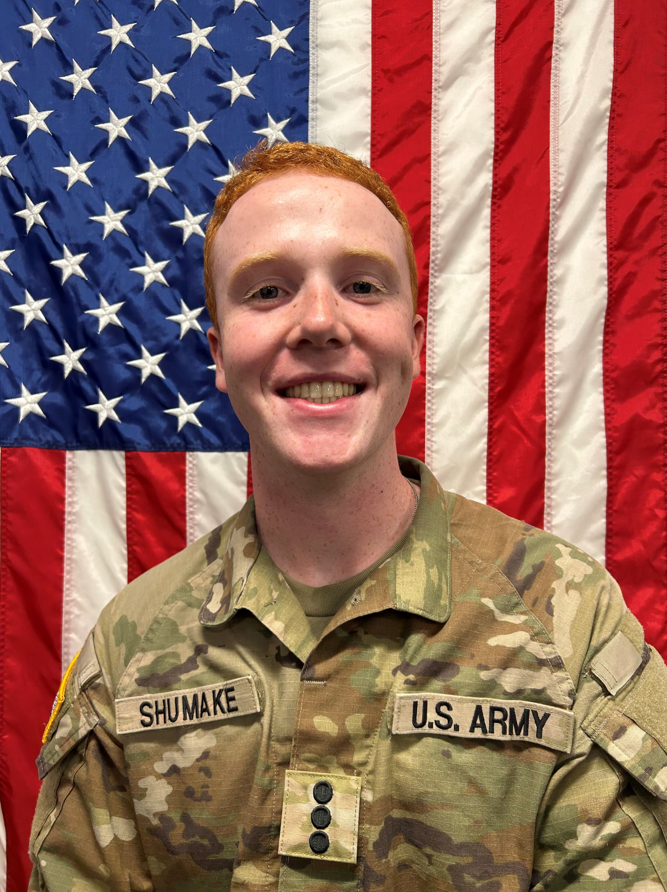 Cadet Shumake standing in front of a U S A flag in uniform.