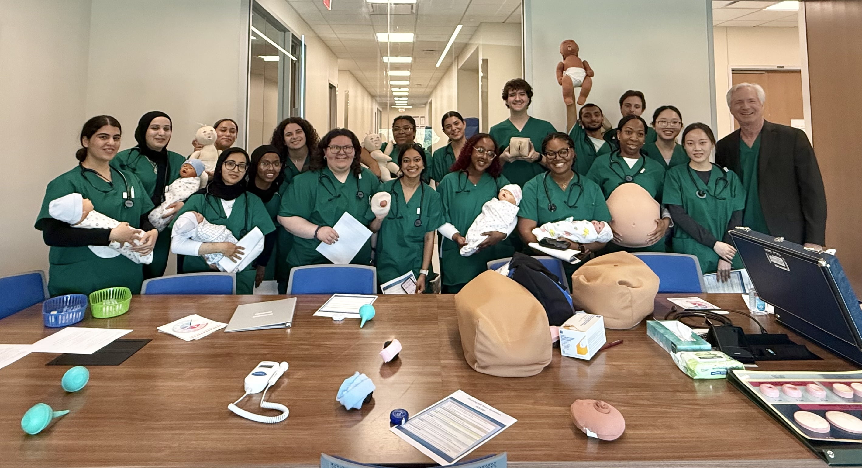 Students in scrubs gathered for a group photo. Some carry fake babies.