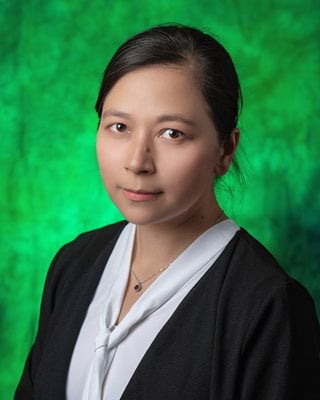 Profile folder of Dr. He, a professor at UNT, wearing a white blouse under a black jacket, and a green background.