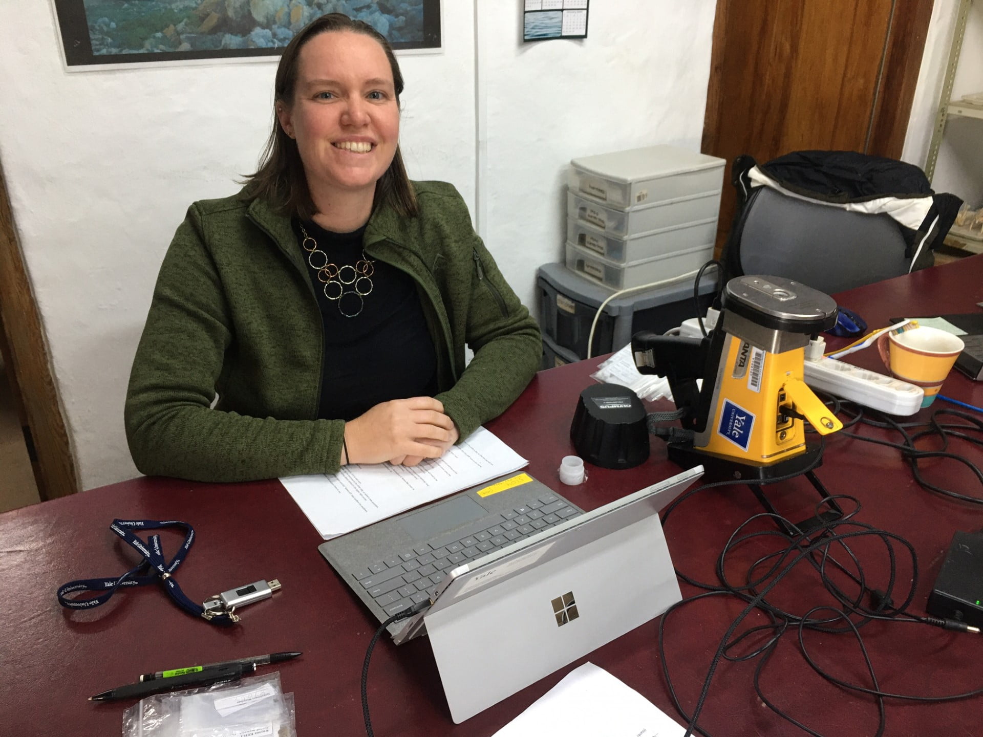 Hannah Keller sitting at a desk, smiling with her hands clasped together
