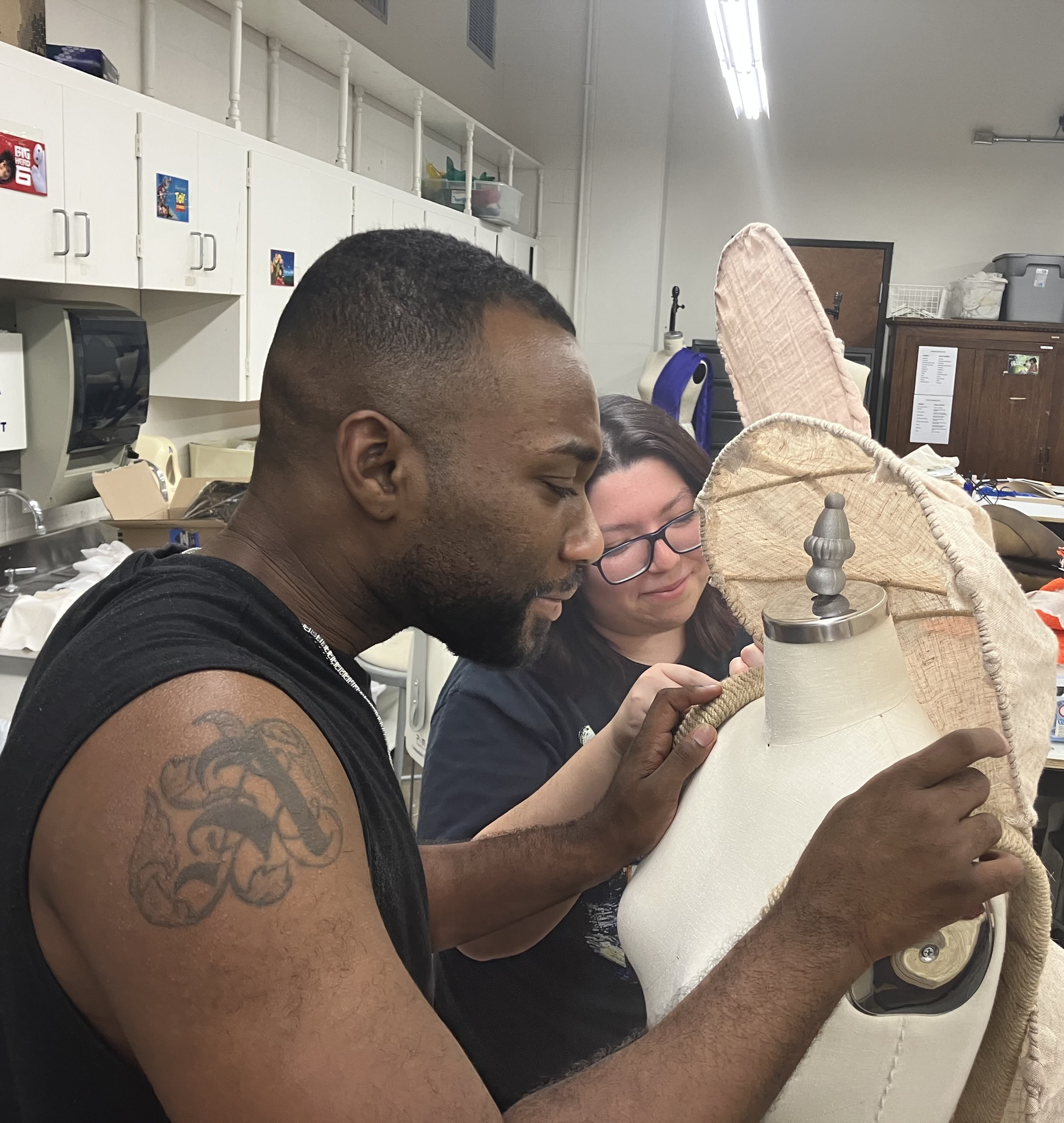 Two students corking on hand-sewing a costume