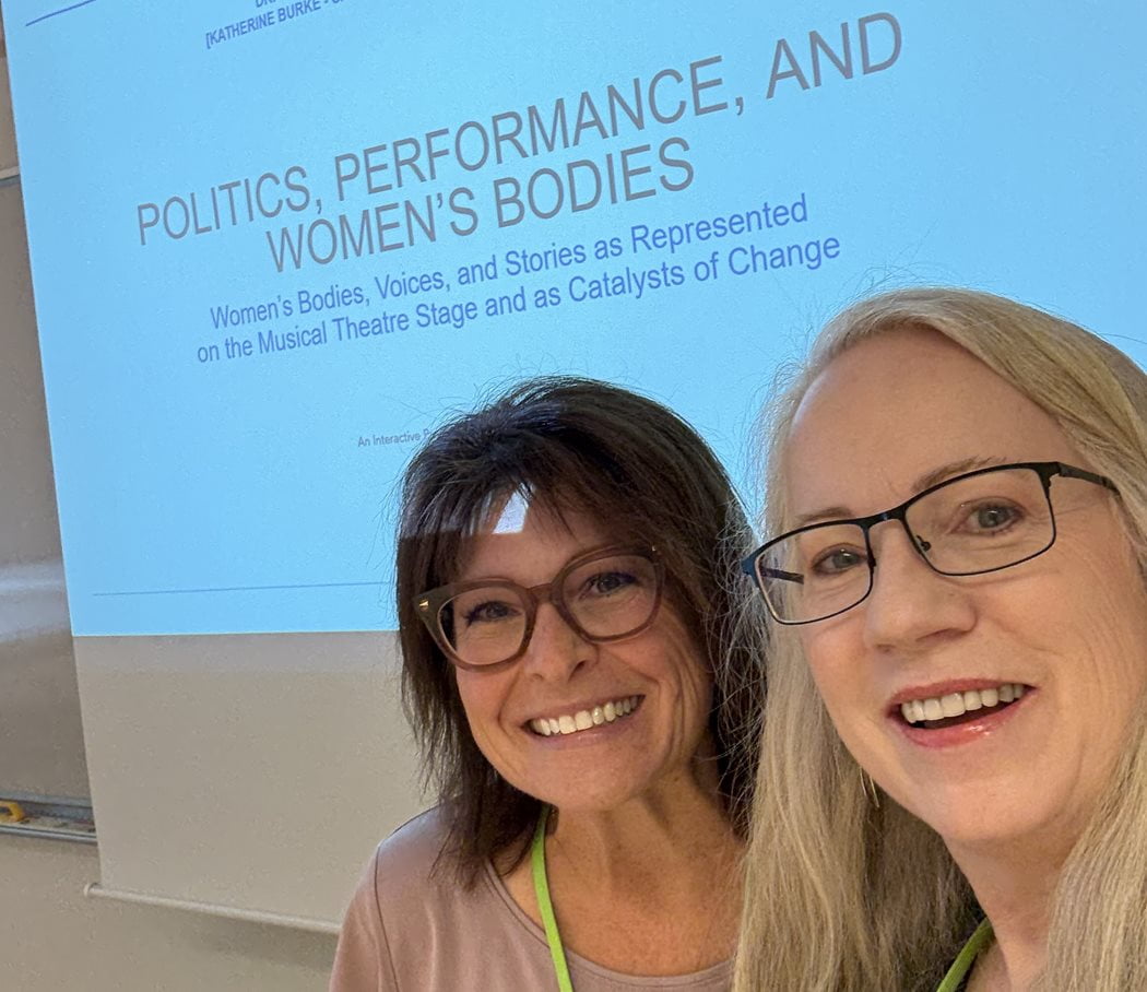 Anne Healy and Brandi Andrade smiling in front of screen which reads "Politics, Performance, and Women's Bodies