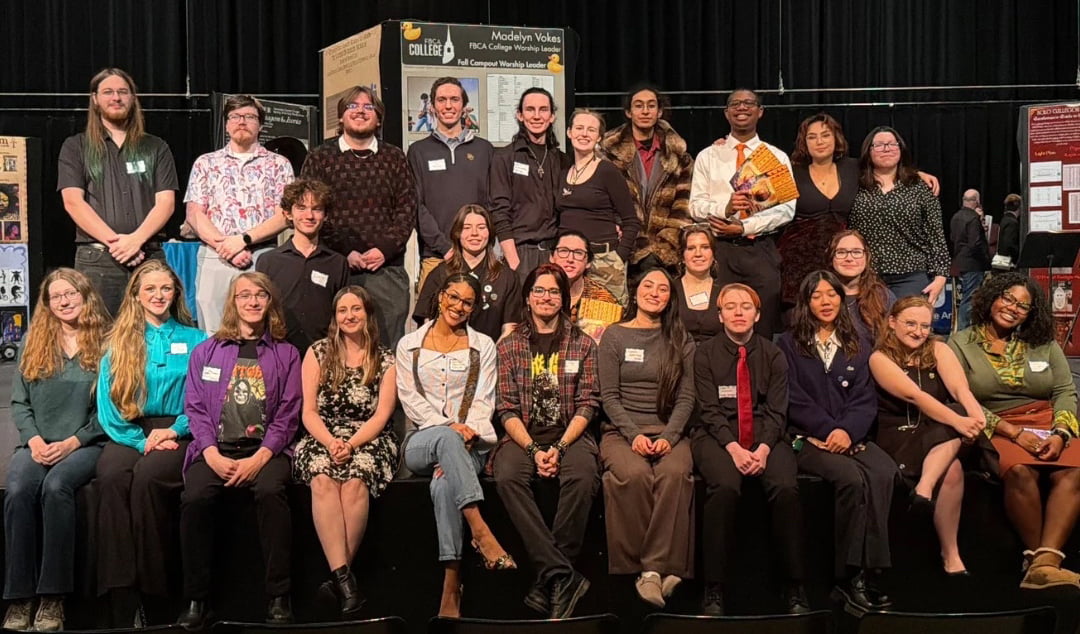 Group of design tech students sitting in front of display on stage