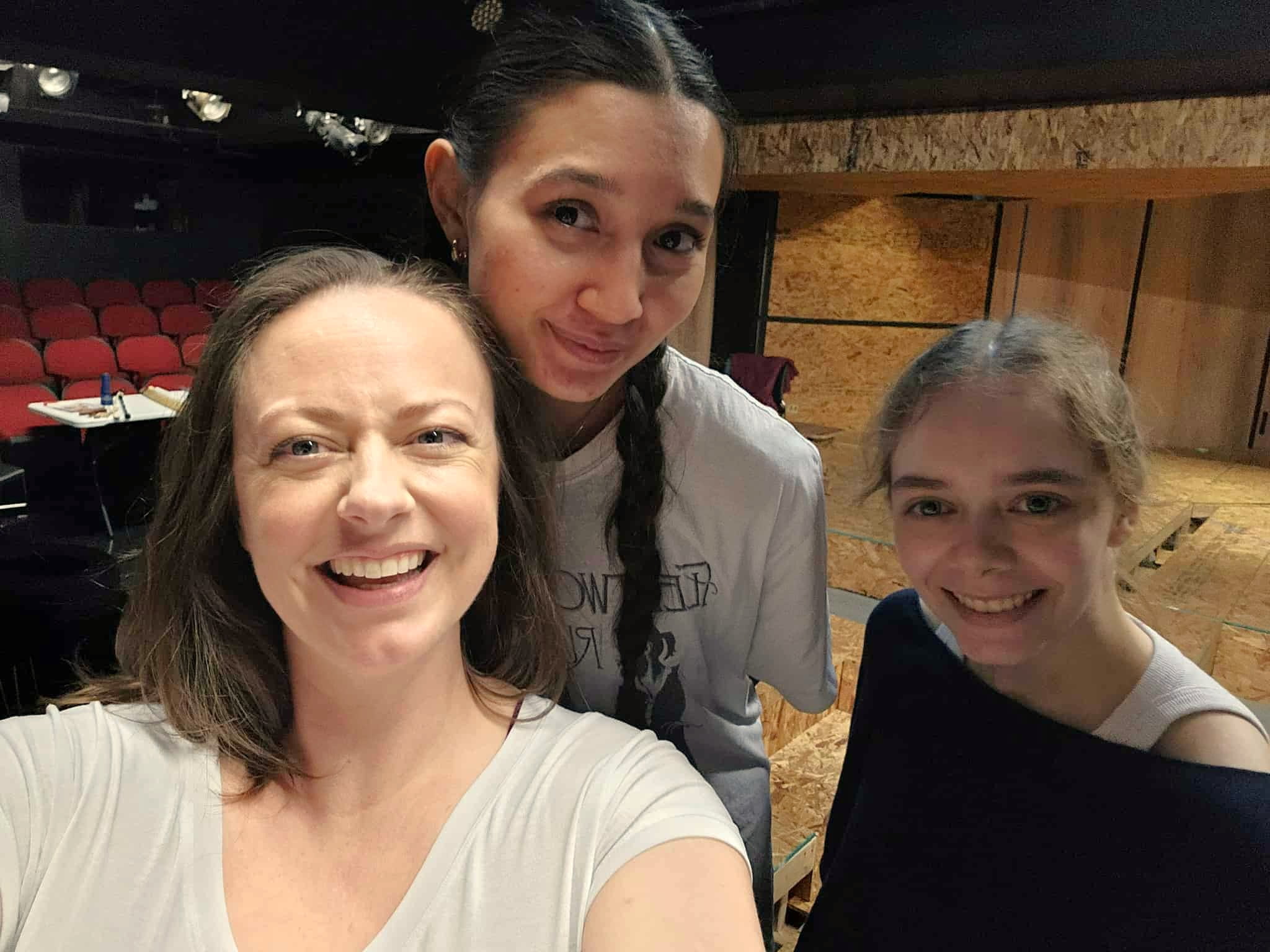 Three people taking a smiling selfie in a theatre