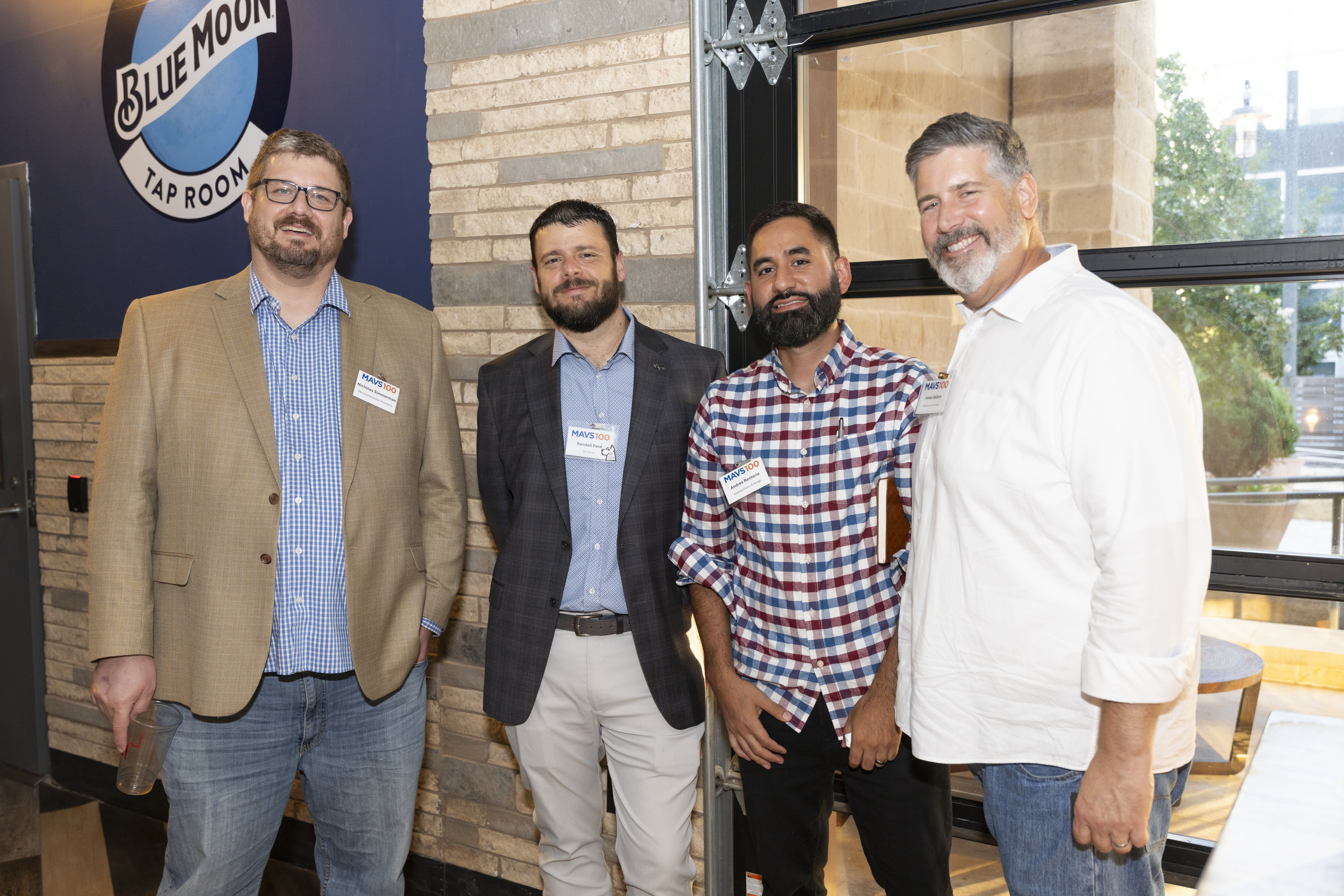 Four attendees pose for a photo in the Blue Room Taproom at Texas Live!.