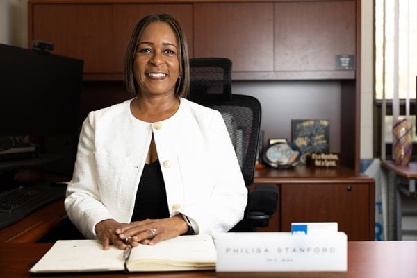 Dr. Philisa Stanford poses for a photo behind her desk. Her hands rest on an open notebook.