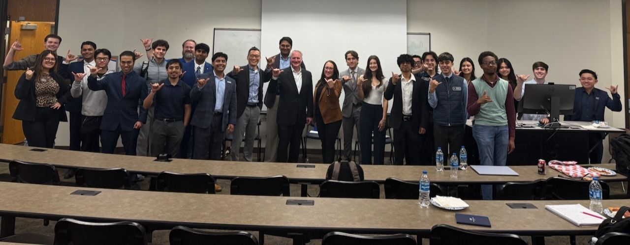 Students and presenters pose in a wide photo in a classroom. 