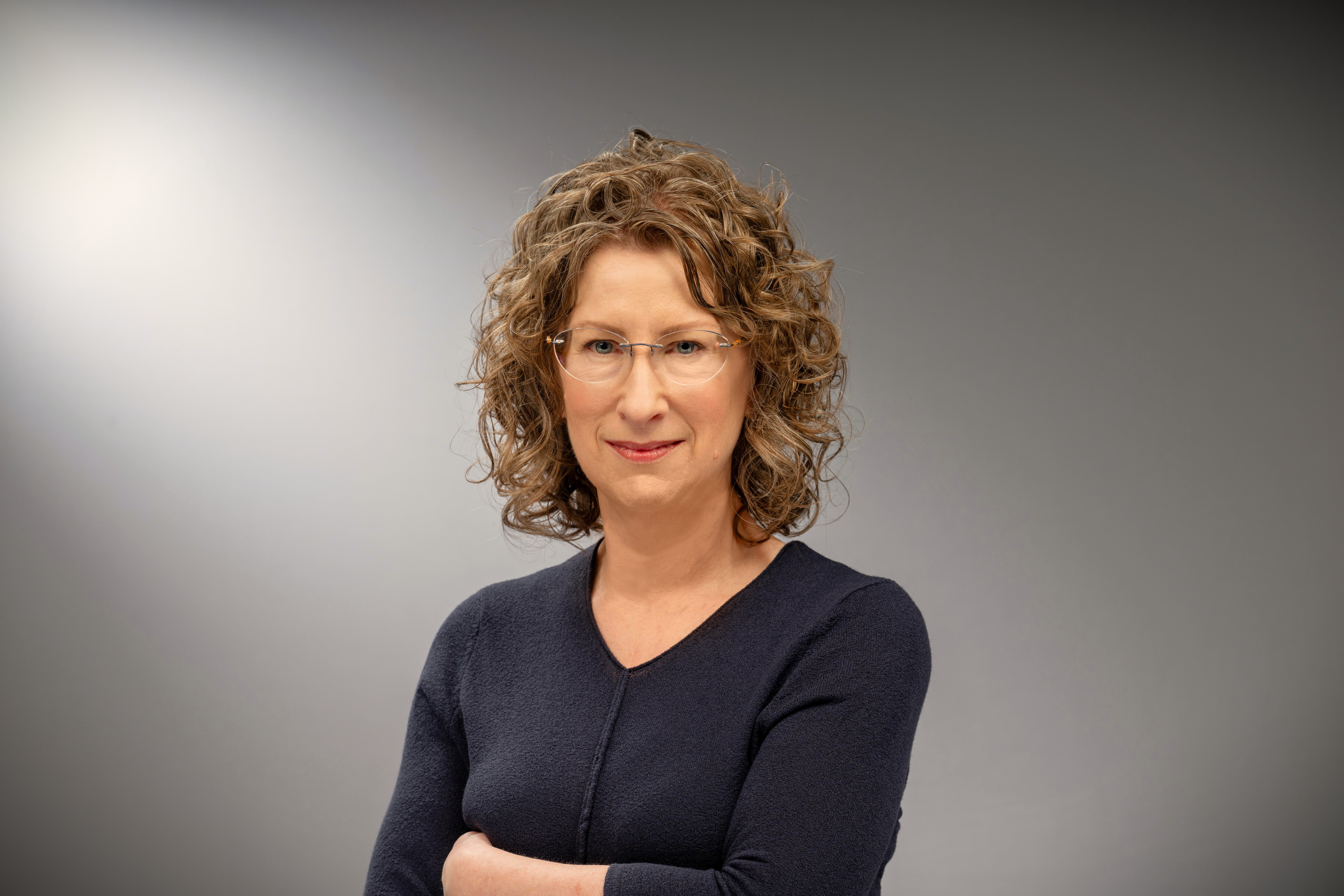 Catherine Hinton poses for a headshot in front of a gray background.