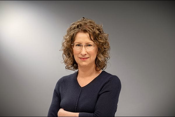 Catherine Hinton poses for a headshot in front of a gray background.