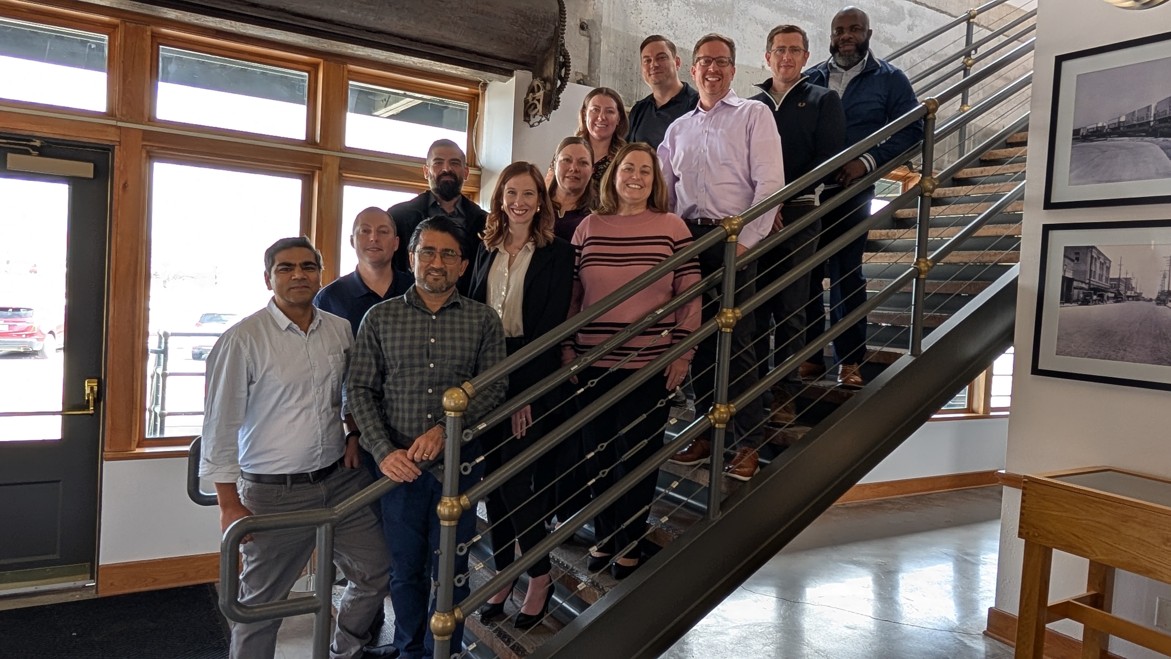 UTA EMBA students pose for a photo while standing on stairs. 