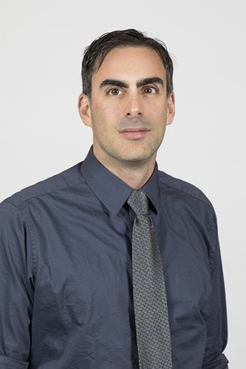 David Rokowski posing for a headshot with a gray background.