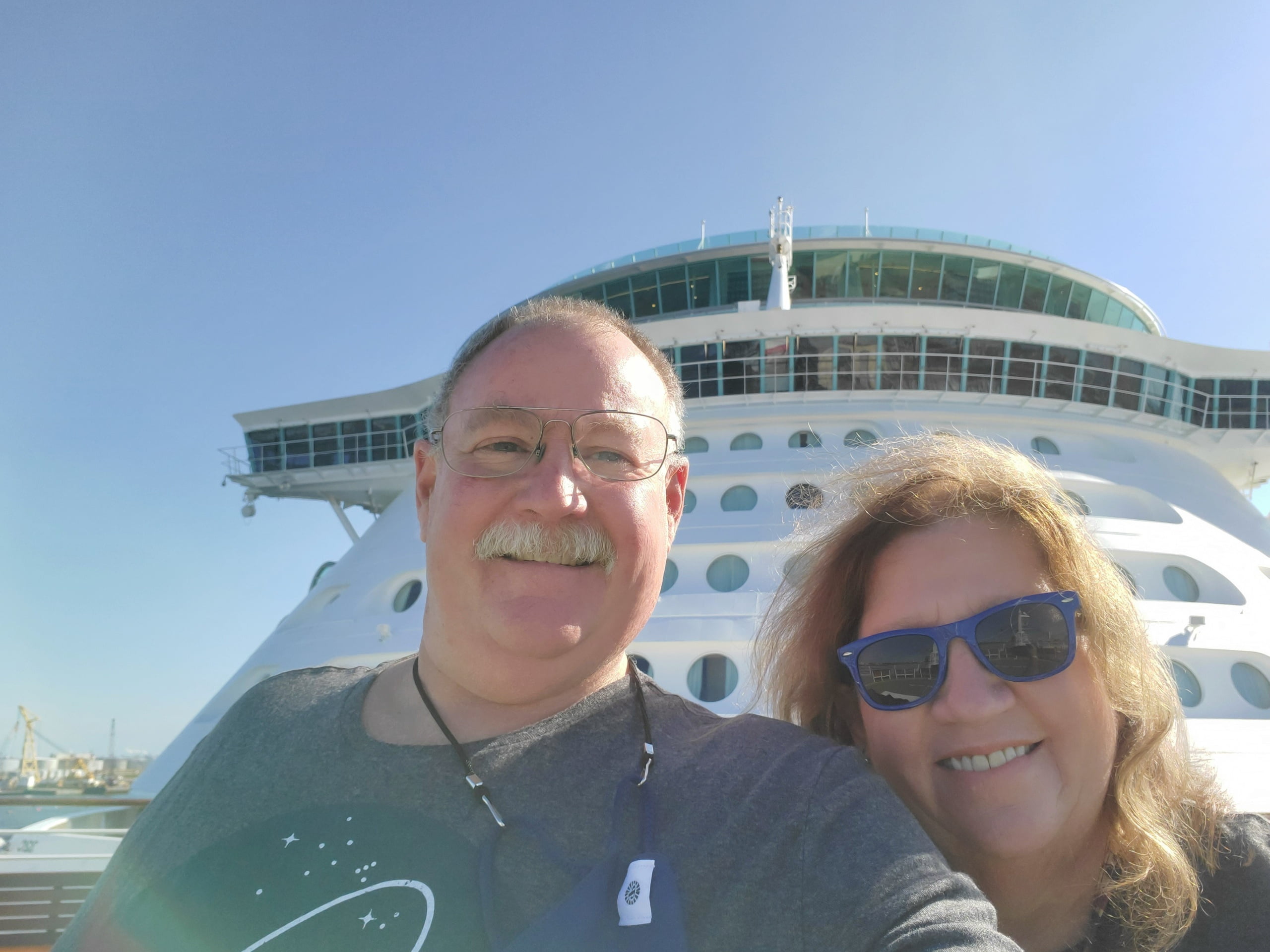 Denise Wylie and her husband pose for a selfie in front of cruise ship.