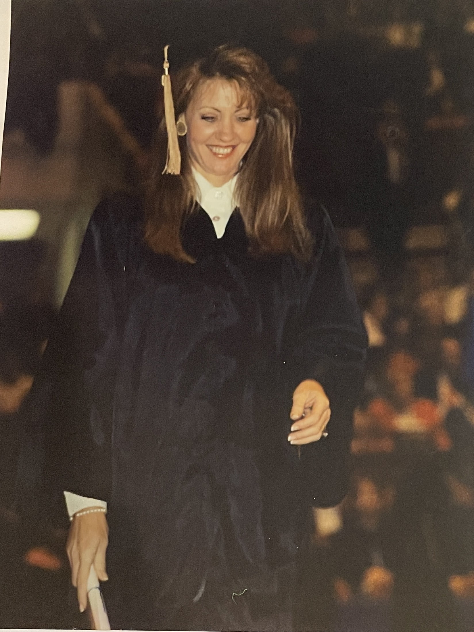 Lesa Bailey walks across the UTA graduation stage, wearing graduation regalia. 