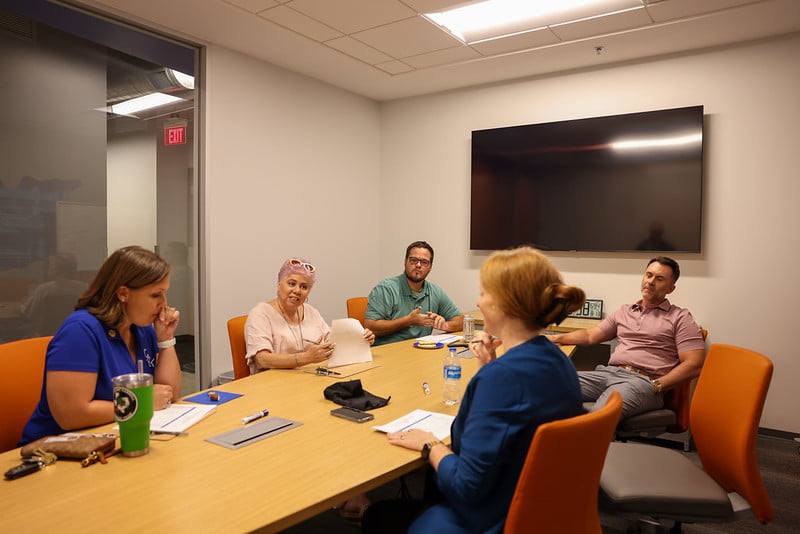 Several MavPitch judges sit around a table deliberating.