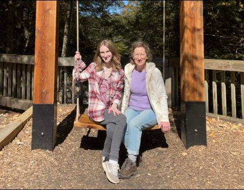 Photo of Catherine Hinton with her daughter on a swing.