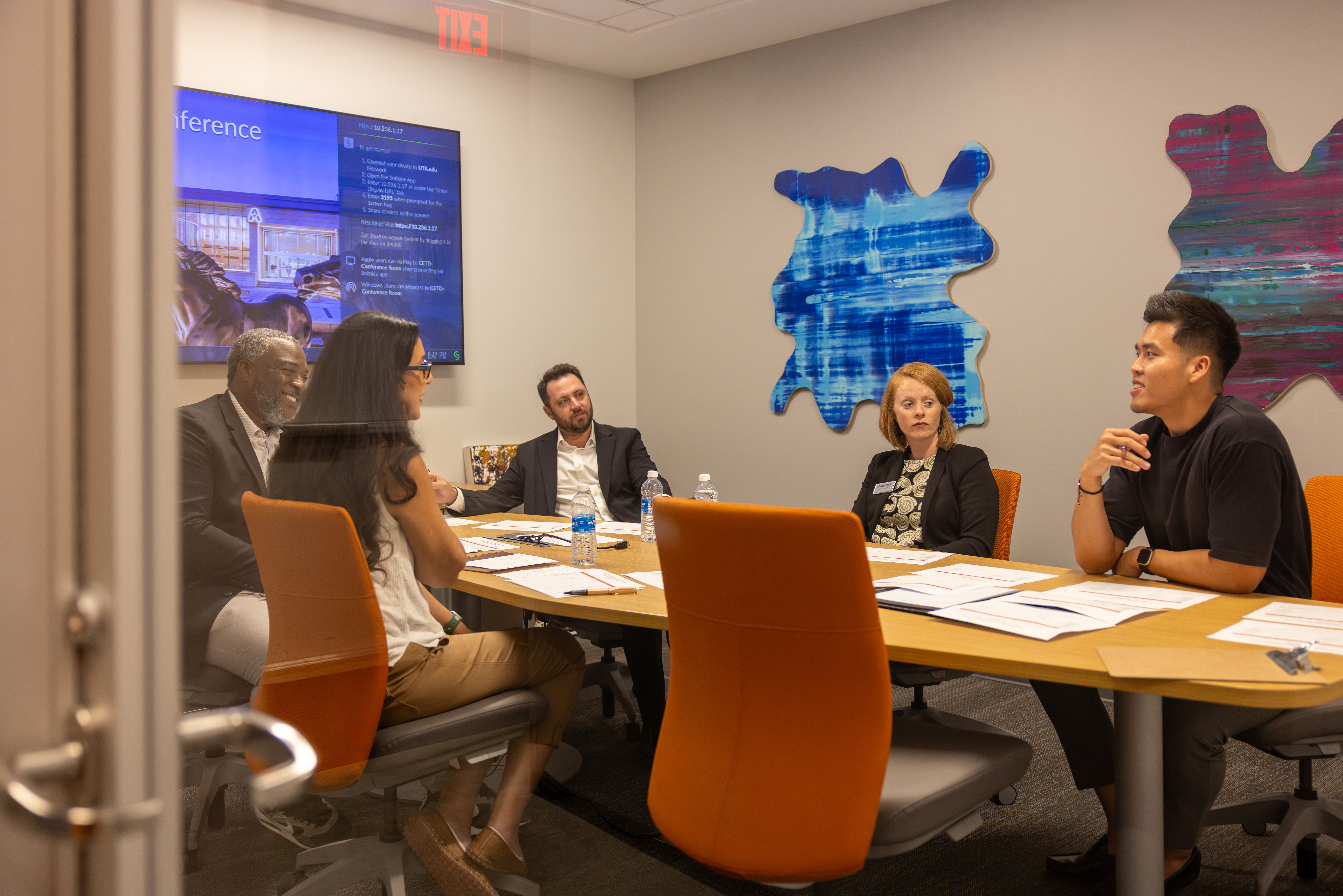 A group of Alumni discuss rankings in a conference room.