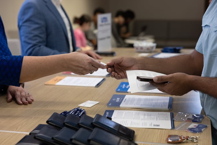A Member of Frost Bank passes a business card to a UTA College of Business student during the Finance and Real Estate Employer’s and Organization’s Week. (Photo by Thomas Johns)