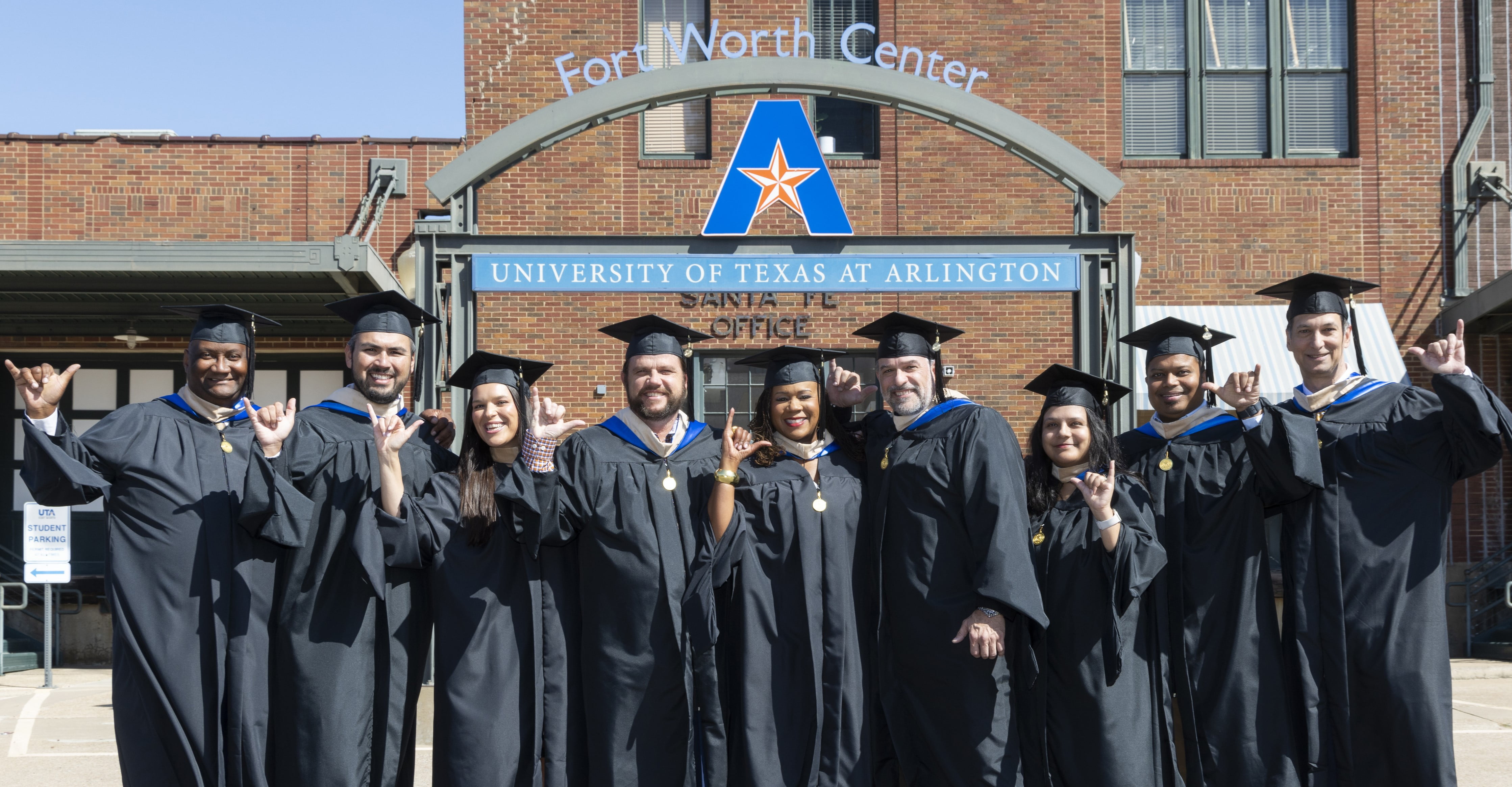 A University of Texas at Arlington Executive Master of Business Administration cohort poses with the “Mav Up” hand sign prior to graduation at the UTA Fort Worth Center. (Photo by Sharon Ellman)