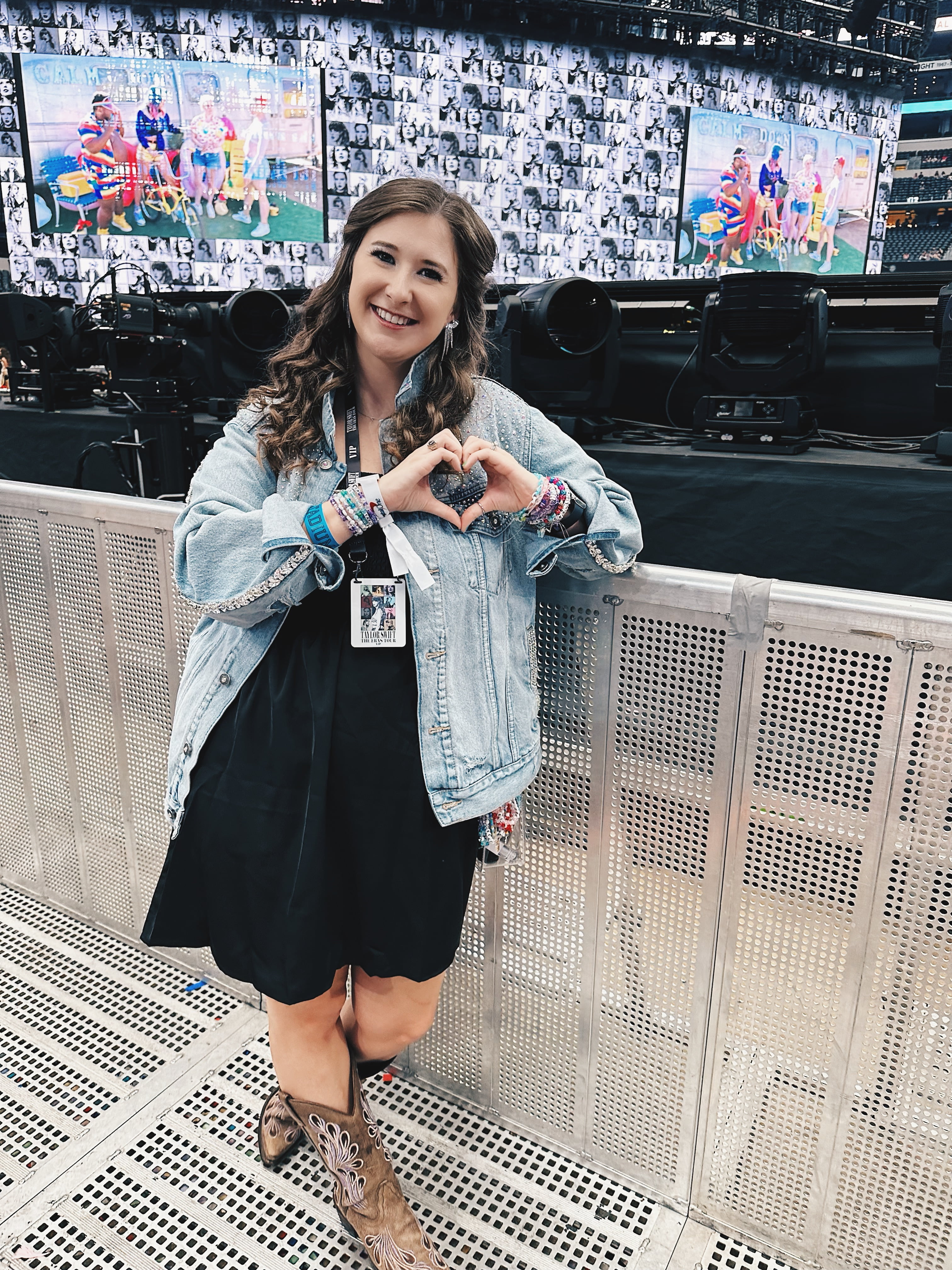 Dr. Santee poses in front of Taylor Swift's "Eras Tour" stage. She is leaning against the barricade and is making a heart pose with her hands.
