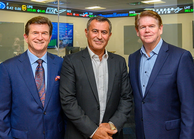 College of Business Dean Harry Dombroski, Sam Mahrouq, and Arlington Mayor Jeff Williams pose in front of the Sam Mahrouq Financial Markets Lab.