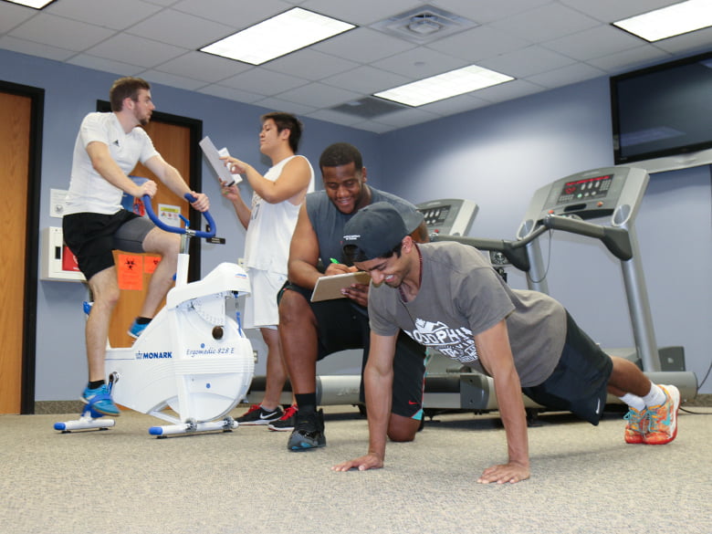 A student monitors the blood pressure of a person on a treadmill.