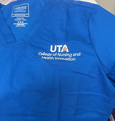 embroidered U T A College of Nursing and Health Innovation logo on royal blue scrubs