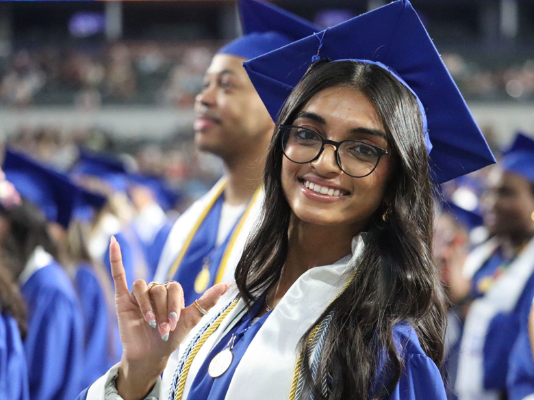 Female student nurse during commencement doing a mav-up sign