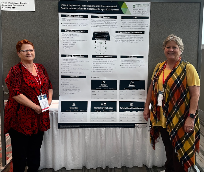 2 female faculty members standing by their poster presentation