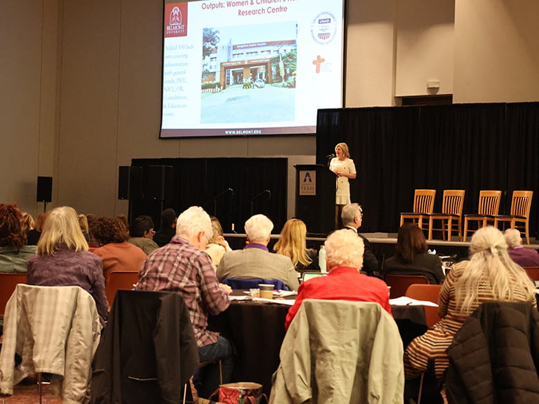 Speaker showing slides in front of onlookers at symposium