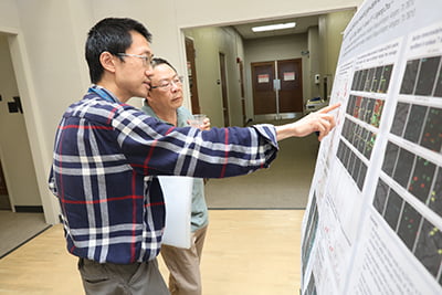 Attendees observing poster at CONHI Research Expo