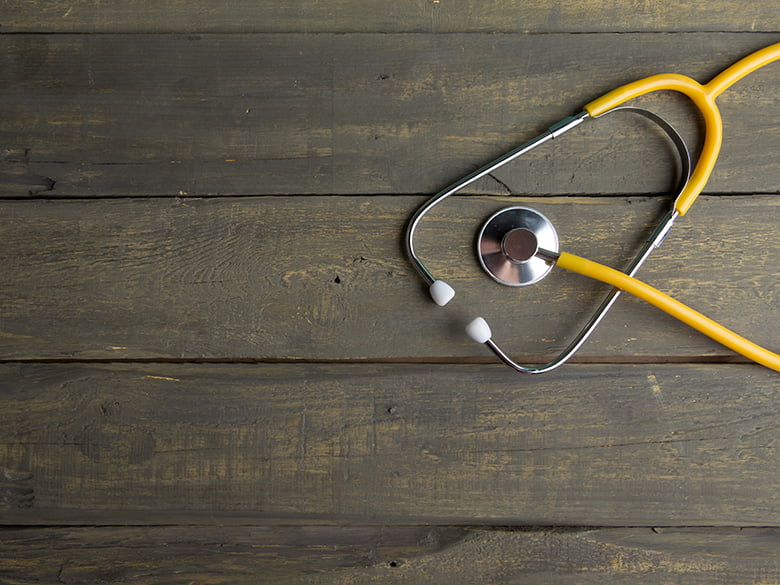 yellow stethoscope on wood table