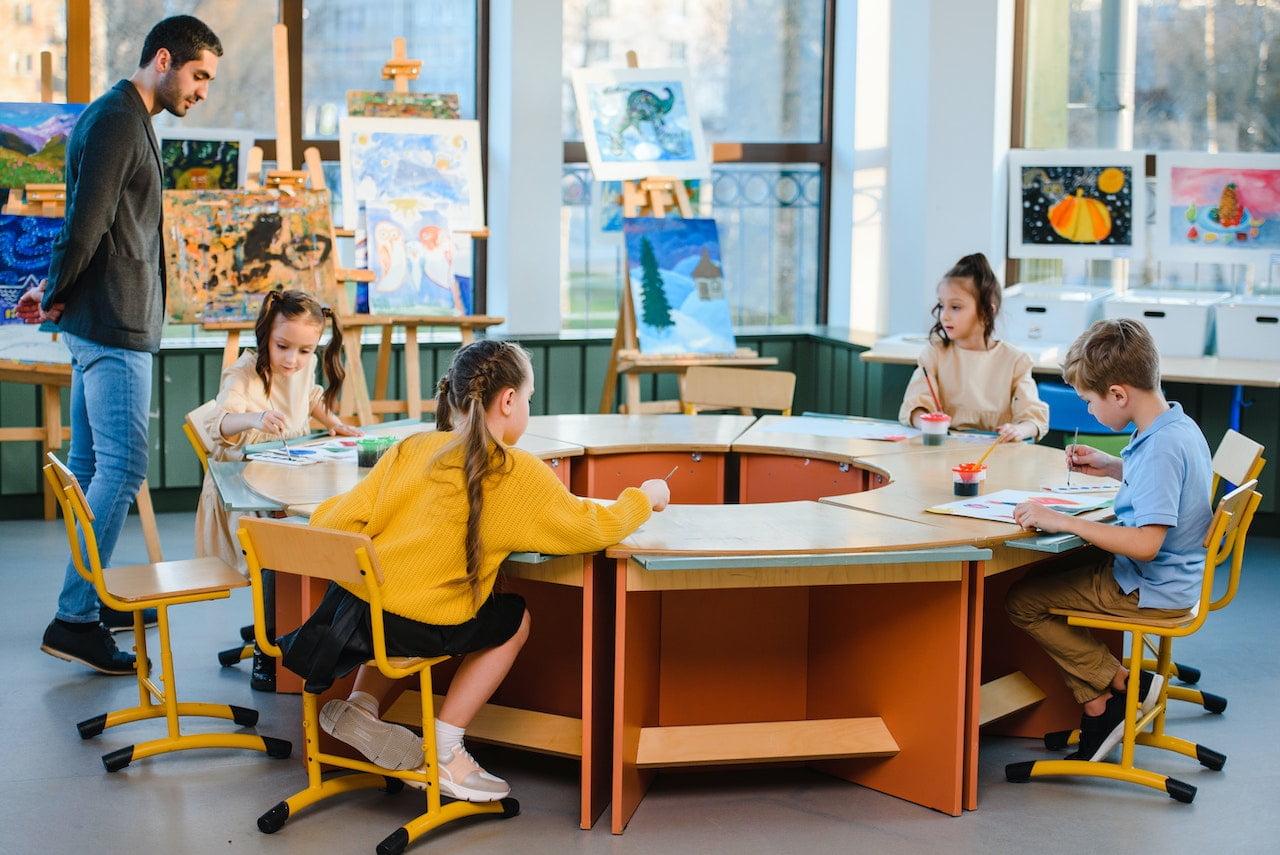 Art teacher walks around students in an art classroom 