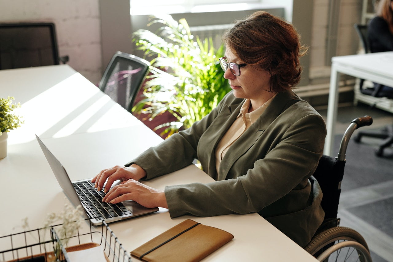 A person in a wheelchair works at a desk