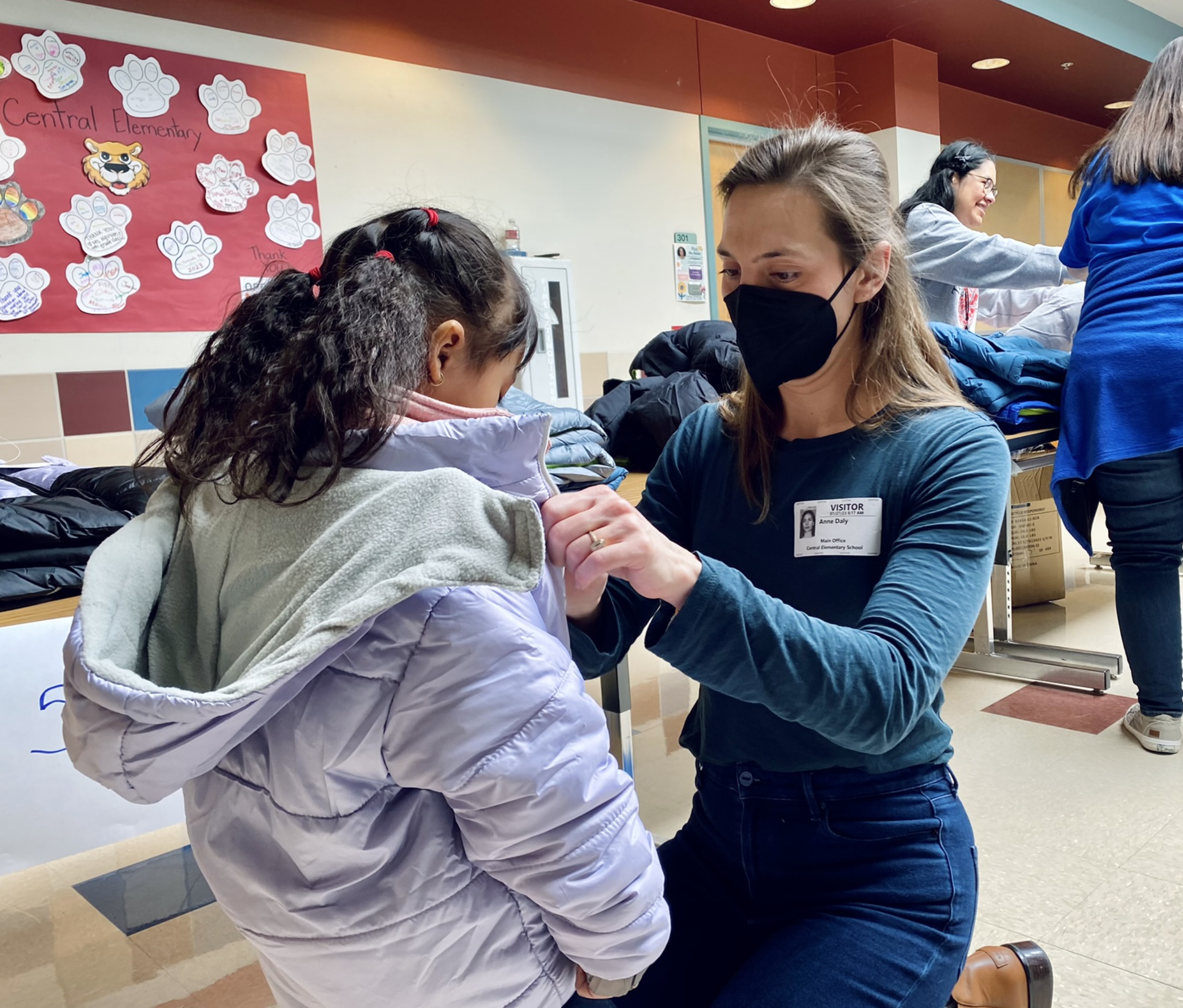 UTA's Annie Daly helps a student try on her new winter coats, donated by Operation Warm