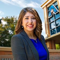 Headshot of University of Texas at Arlington employee Elsa Camargo. The background shows a UTA campus sign.