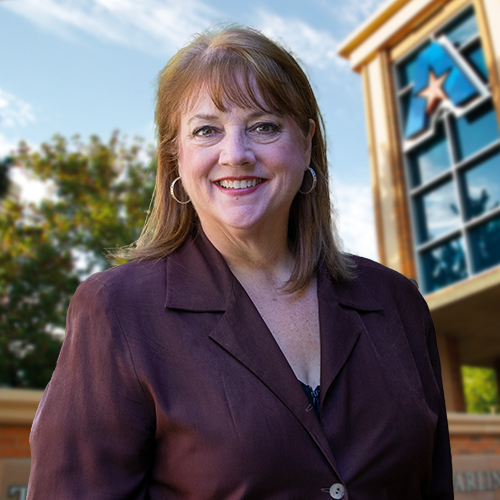 Headshot of University of Texas at Arlington employee Teresa Taber Doughty. The background shows a UTA campus sign.