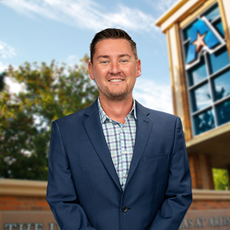 Headshot of University of Texas at Arlington employee Joel Leader. The background shows a UTA campus sign.