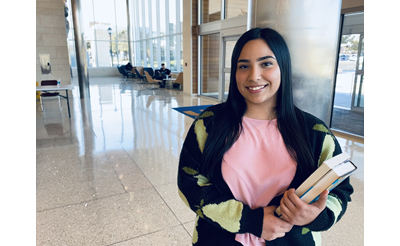 Student posing for a photo in the UC holding books