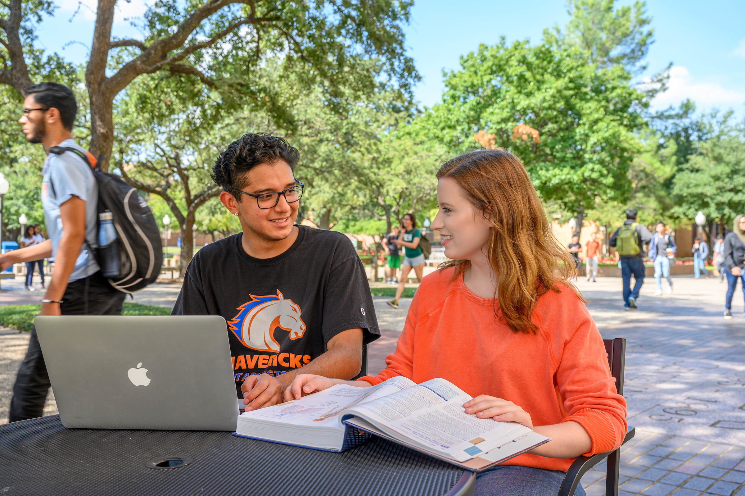 Two University of Texas at Arlington students studying together with books and a laptop 