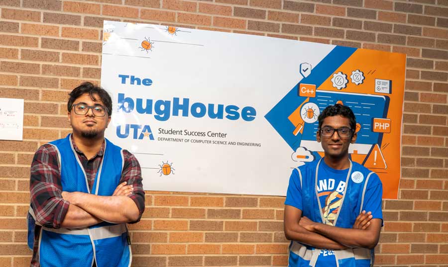 Two student tutors standing by a banner promoting the bugHouse