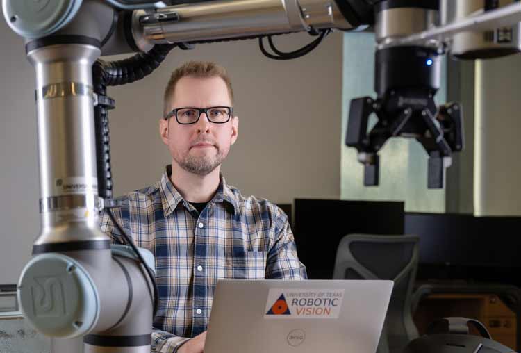 a computer engineering researcher with his laptop and robot arm