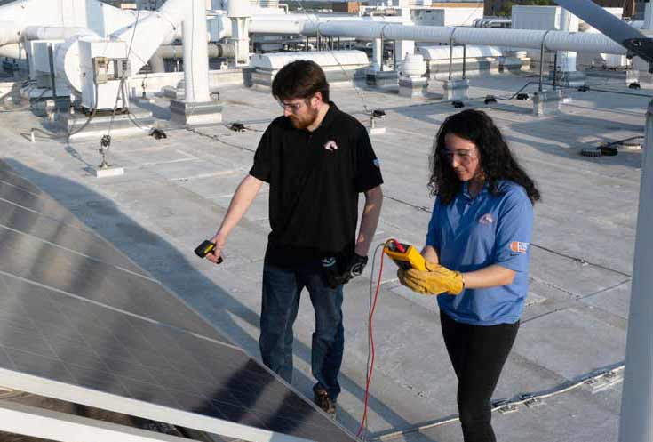 Two electrical engineering researchers perform checks on solar panels