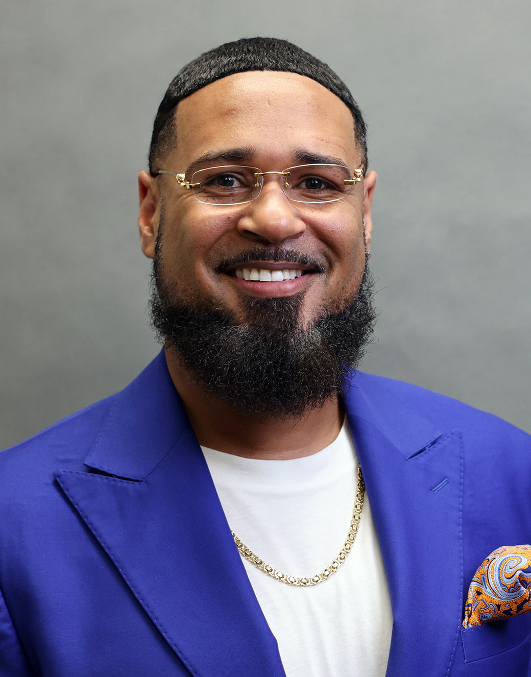 Asst Dean for Development Myrshem George, a bearded man wearing a bright blue jacket and glasses