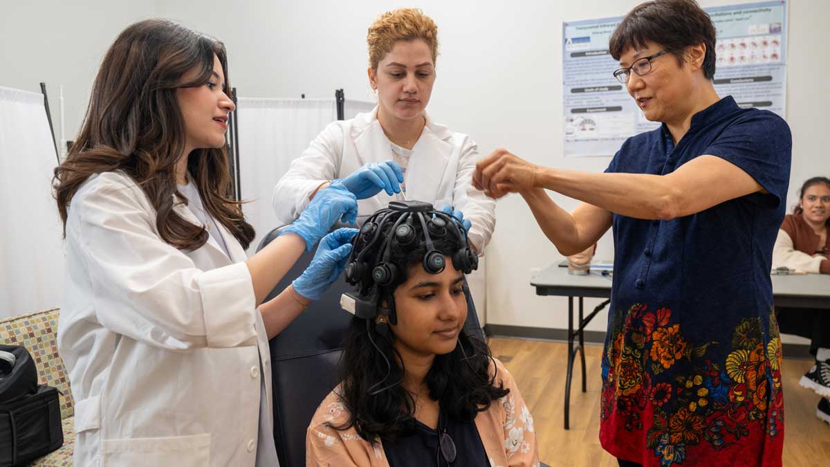 Three researchers with wires connected to the head of a female subject.