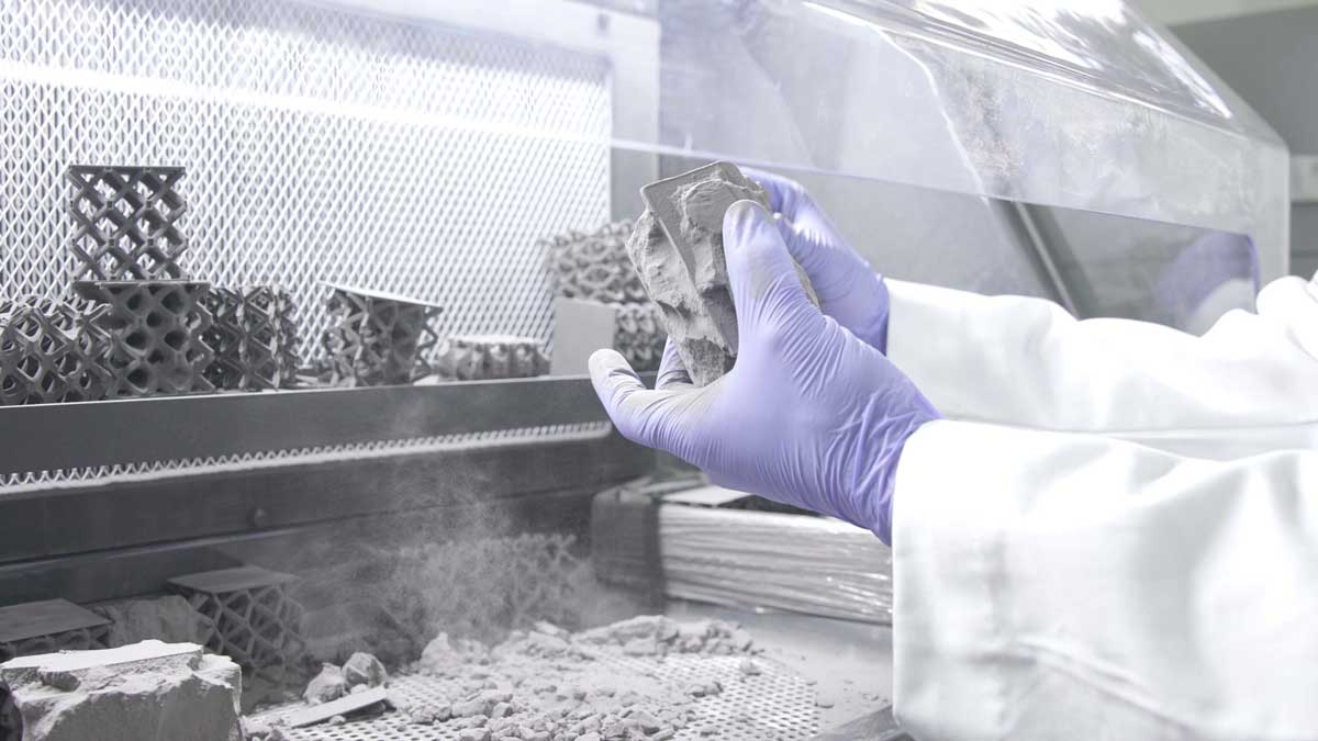researcher in a lab with gloved hands under a hood.